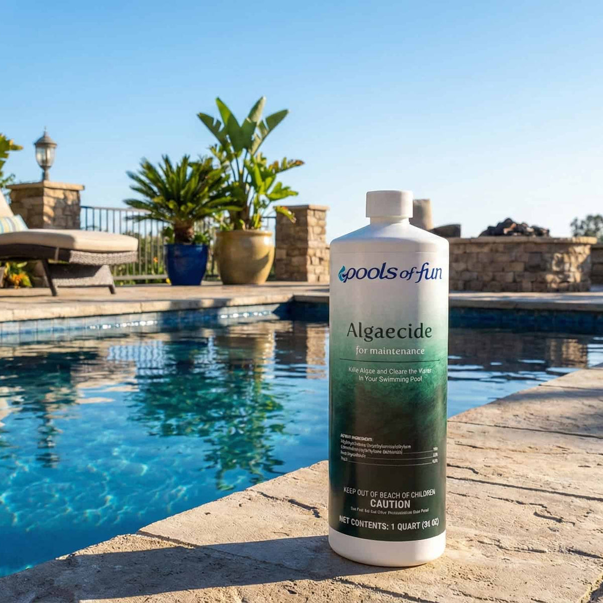 Pool cleaner bottle labeled 'Algaecide' by 'Pool Pro' on a pool deck with a pool and lounge chairs in the background.