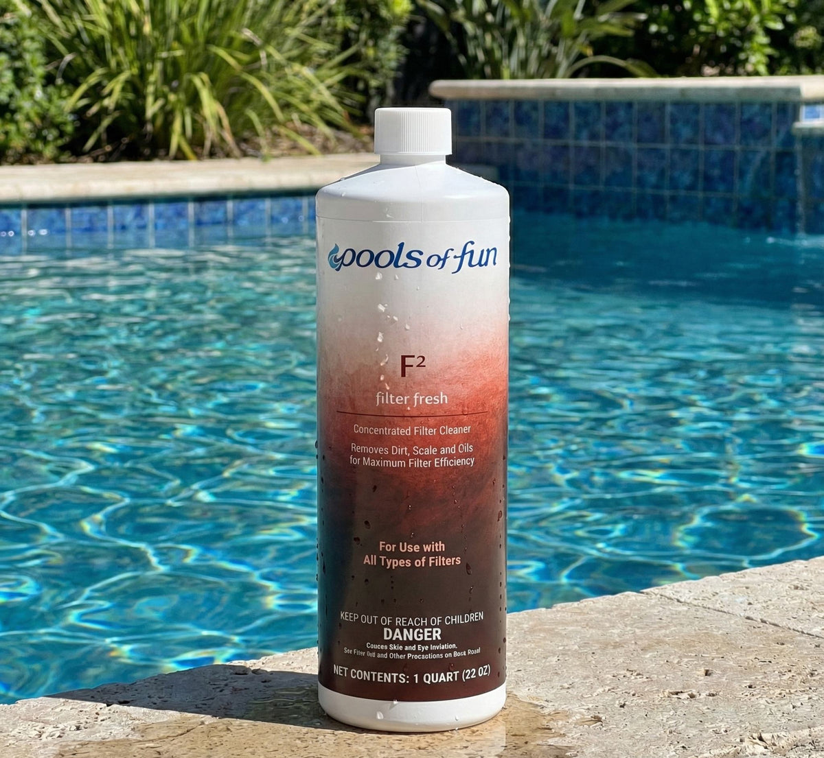 Bottle of 'Pools of Fun' pool filter freshener by a pool