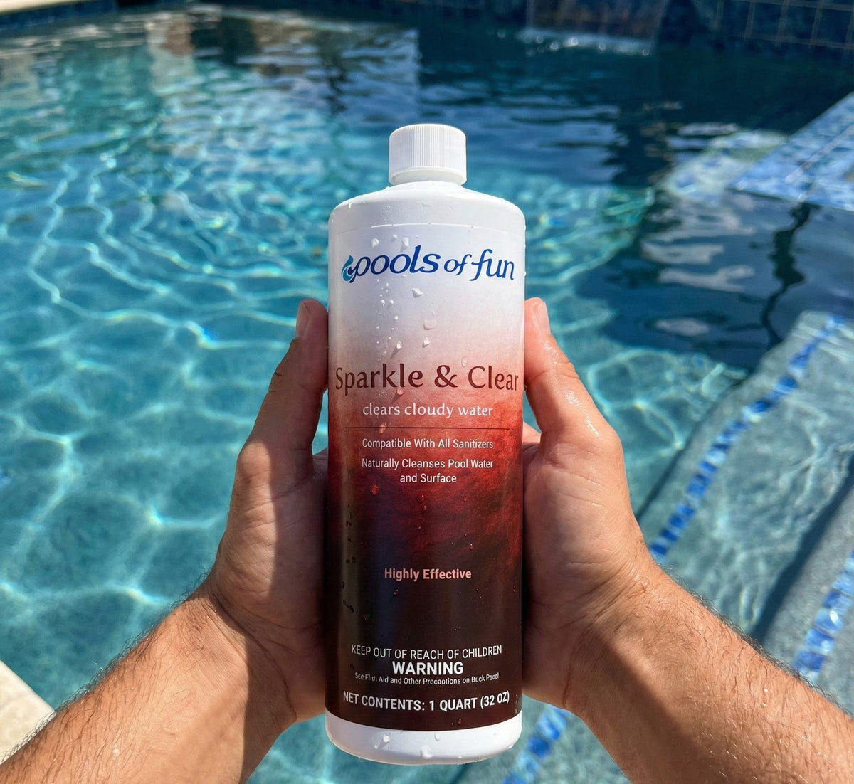 Person holding a bottle of 'Pools of Fun Sparkle & Clean' by a pool.